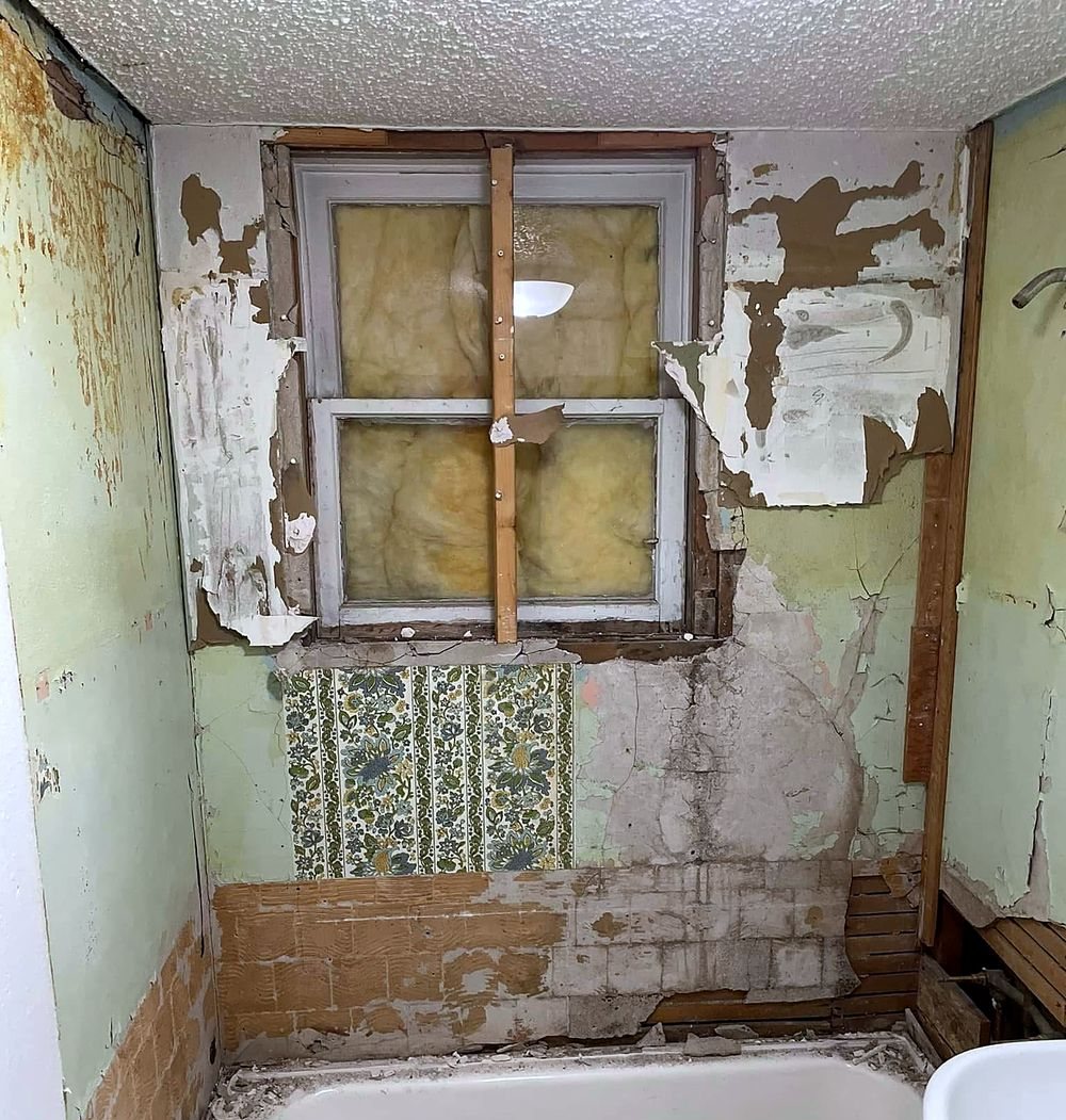 Bathroom before — walls stripped to plaster, the original tub still in place